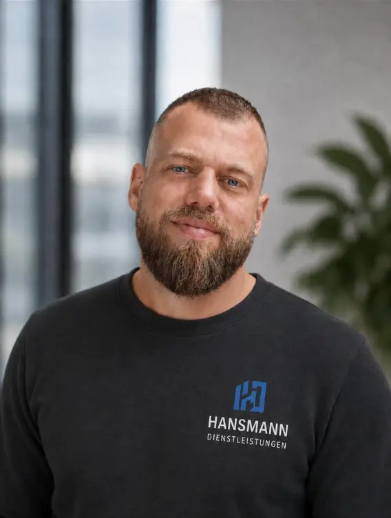 Michael Hansmann in Arbeitskleidung mit dem Firmenlogo der Gebäudereinigung Hansmann Dienstleistungen in Köln